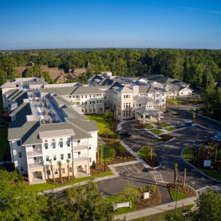 Aerial view of a residential complex surrounded by trees and clear blue skies.
