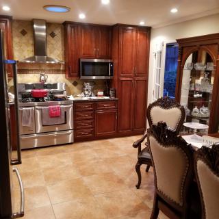 A stylish modern kitchen with wooden cabinets, stainless steel appliances, and an adjacent dining area.