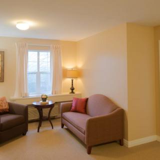 A cozy living room with two sofas, a lamp, and a window providing natural light.