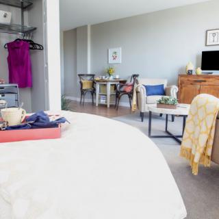 A cozy and open living space featuring a combination of bedroom and sitting area furniture.