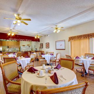 A cozy dining room with elegantly set tables and ceiling fans.