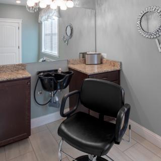 A modern hair salon setup featuring a barber chair, sink, and mirrors.