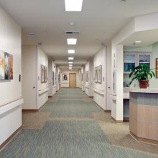 A clean and well-lit hospital corridor with artwork on the walls and a reception desk.