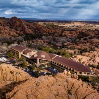 An aerial view of a hotel nestled among stunning desert rock formations under a cloudy sky.