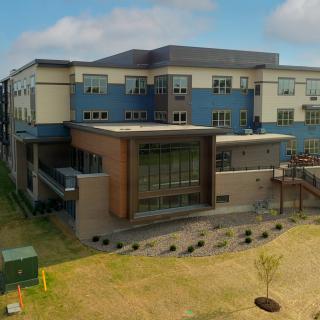 A modern school building with a landscaped exterior under a cloudy sky.