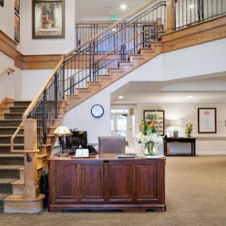 A welcoming lobby with a wooden staircase and reception desk, featuring modern decor and ample lighting.