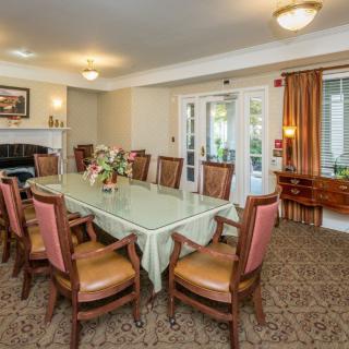A well-appointed dining room with a large table surrounded by chairs, featuring elegant decor and natural lighting.