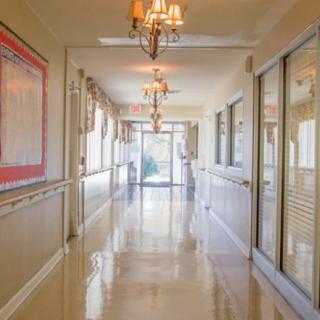 A brightly lit hallway with chandeliers and glass doors at the end.