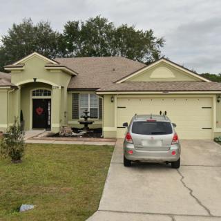 A single-story residential house with a car parked in the driveway.