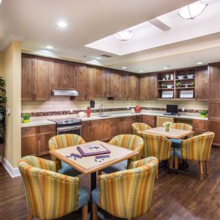 A modern kitchen and dining area with wooden cabinets, round tables, and upholstered chairs.