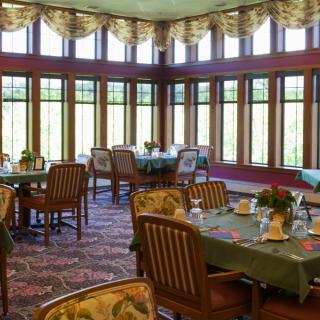 A beautifully decorated dining area with tables and chairs, surrounded by large windows.
