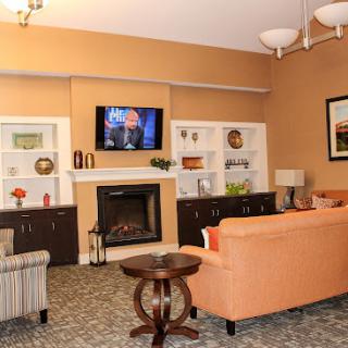 A cozy living room featuring an orange sofa, a fireplace, and a television mounted on the wall.