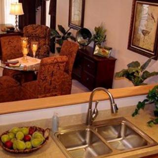 A cozy kitchen view with a double sink and a dining area in the background, featuring warm lighting and elegant decor.