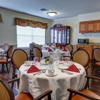 A cozy dining room with elegantly set tables and a view of the kitchen cabinets.