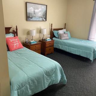 A cozy bedroom with twin beds, each adorned with blue bedding and decorative pillows, accompanied by matching nightstands and lamps.