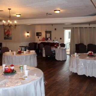 A decorated event space with round tables, chairs, and chandeliers.