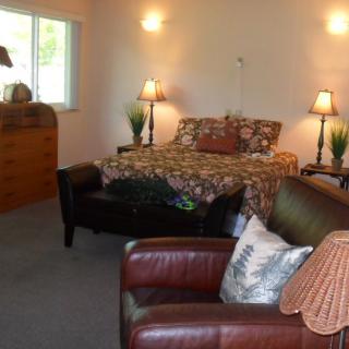 A cozy bedroom with a comfortable bed, leather chairs, and warm lighting.