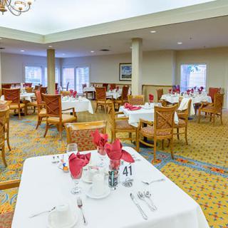 A spacious dining room with elegantly set tables and chairs.