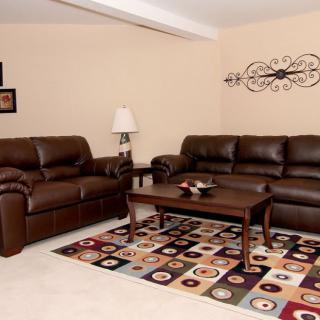 A cozy living room with brown leather sofas and a colorful area rug.