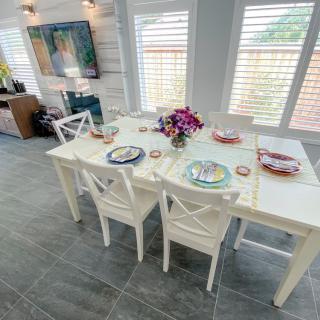 A bright and modern dining room featuring a white table set with colorful plates and a floral centerpiece.