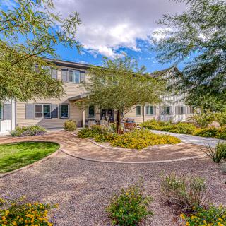 A beautiful house surrounded by a landscaped garden with trees and a clear blue sky.