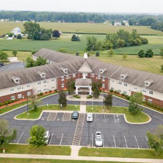 Aerial view of a large building with a parking lot, surrounded by countryside.