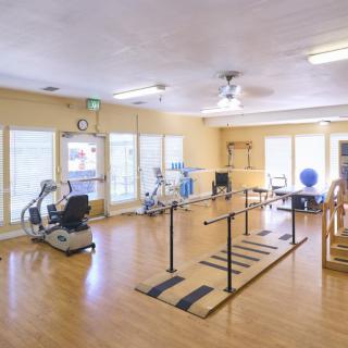 A spacious rehabilitation room equipped with various exercise machines and therapy tools.