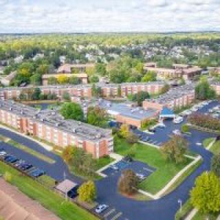 Aerial view of a suburban residential area with multiple buildings and parking lots surrounded by trees.