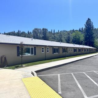 A single-story building with a parking lot and surrounding trees under a clear blue sky.