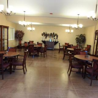 A spacious dining room with several tables and chairs, featuring warm lighting and elegant decor.