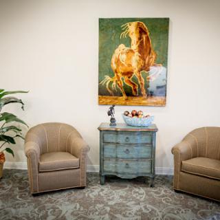 A cozy waiting area featuring comfortable seating, a stylish side table, and an eye-catching piece of artwork.