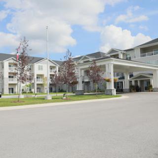 A modern hotel building with a welcoming entrance under a sunny, partly cloudy sky.