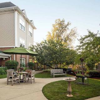A cozy backyard with outdoor seating, lush trees, and a well-maintained lawn.