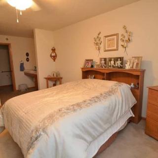 A cozy bedroom with a neatly made bed and wooden furniture.