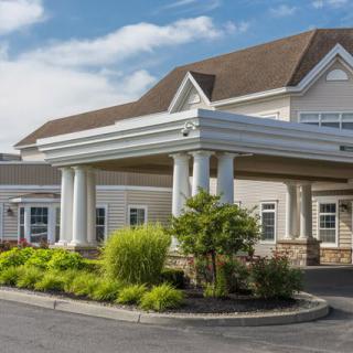A well-maintained building entrance with columns and landscaped greenery.