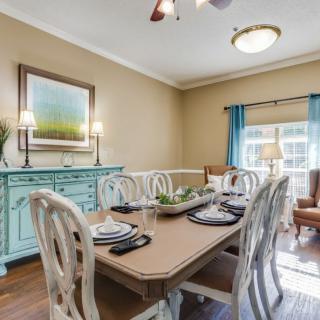 A well-decorated dining room with a wooden table, ornate chairs, and a turquoise sideboard beneath a landscape painting.