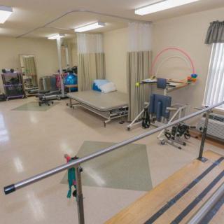 A physical therapy room equipped with parallel bars and rehabilitation equipment.