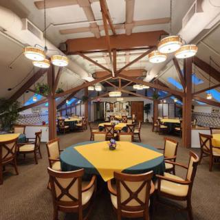 A spacious restaurant dining area with neatly arranged tables and decorative ceiling beams.