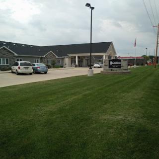A view of a modern building surrounded by well-maintained grass and parking spaces.
