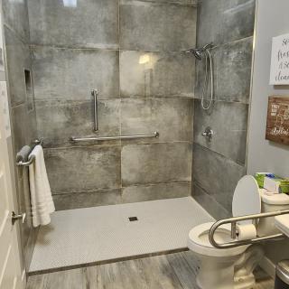 A modern, accessible bathroom with tiled walls and handrails.
