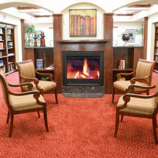 A cozy library seating area with a fireplace and four chairs.