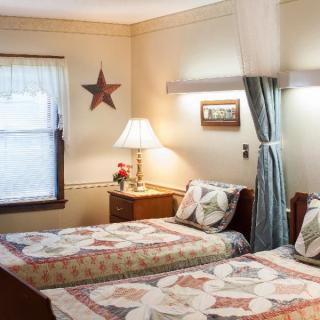 A cozy bedroom with twin beds and vintage decor, featuring quilted bedspreads and a star wall decoration.
