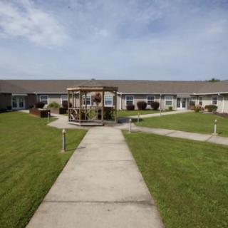 A courtyard with a central gazebo and pathways surrounded by a building and well-maintained lawns.