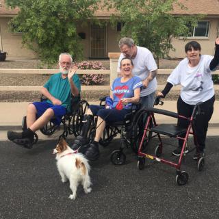 A group of people outdoors with wheelchairs and a dog.