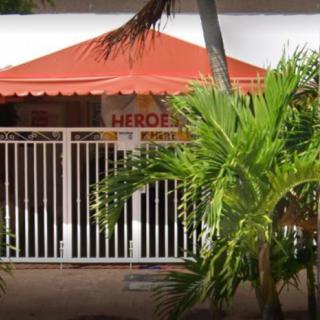 A gated building with an orange awning and palm trees in front.