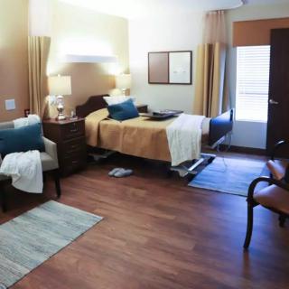 A cozy bedroom featuring a single bed, wooden flooring, and warm lighting with decorative elements.