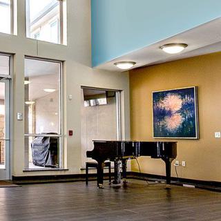 A modern interior with a grand piano and an abstract painting on the wall.