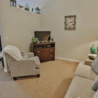 A cozy living room with a sofa, armchair, and television.