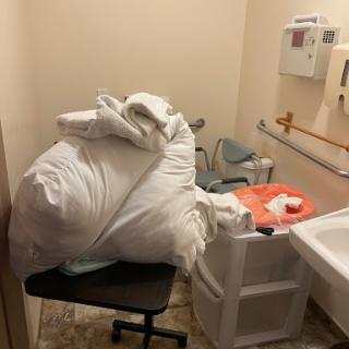 A pile of laundry and supplies cluttering a small hospital room.