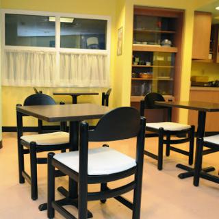 A cozy dining area with black wooden tables and chairs against a warm yellow backdrop.